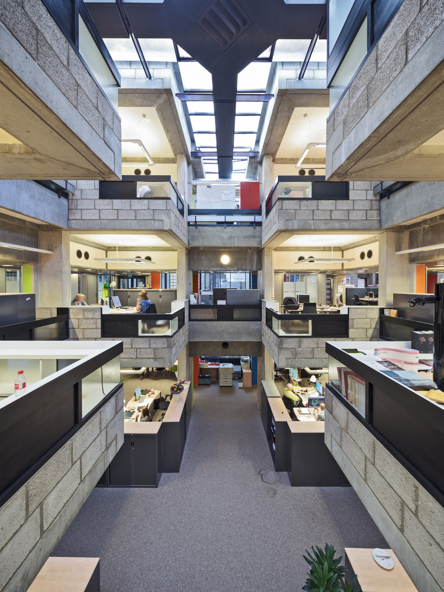 Centraal Beheer in Apeldoorn, designed by Herman Hertzberger in 1972. Hertzberger stacked small concrete work modules around open voids, engineering paths that force employees to walk past, and look down upon, dozens of colleagues when moving between desks.