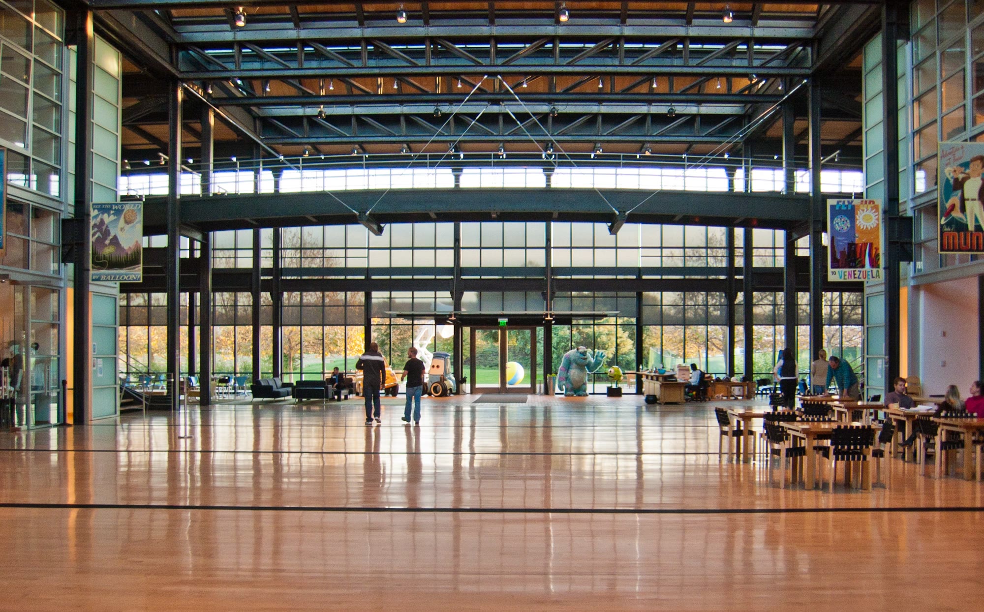 The grand atrium at Pixar's Emeryville campus, opened in 2000. By centralizing essential shared amenities, including mailboxes, meeting rooms, the cafe, and restrooms, the architecture guarantees that staff from all departments must repeatedly cross paths throughout the workday.